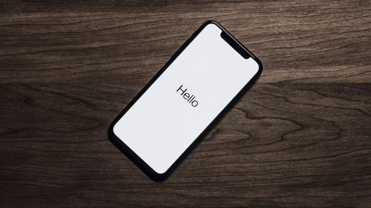 Téléphone posé sur un bureau en bois, écran allumé sur un message d'accueil
